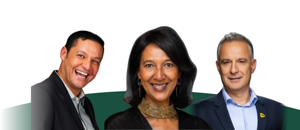 Three people pose against a white and dark green background. A man on the left wears a dark blazer, a woman in the centre wears a black top and a gold textured collar necklace, and a man on the right wears a navy blazer with a small yellow pin on his lapel. All three are smiling.